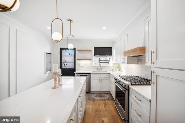 kitchen featuring light wood-type flooring, stainless steel appliances, sink, decorative light fixtures, and white cabinetry