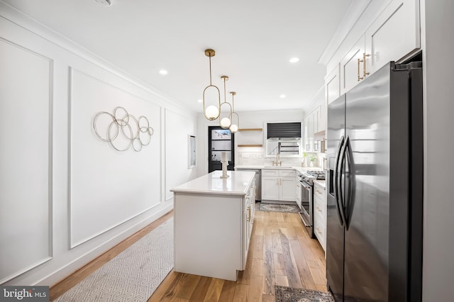 kitchen with appliances with stainless steel finishes, pendant lighting, a center island, light hardwood / wood-style floors, and white cabinetry