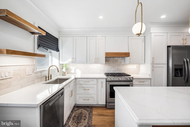 kitchen with hanging light fixtures, sink, light stone countertops, appliances with stainless steel finishes, and white cabinetry