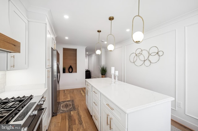 kitchen with appliances with stainless steel finishes, light hardwood / wood-style flooring, white cabinets, a center island, and hanging light fixtures