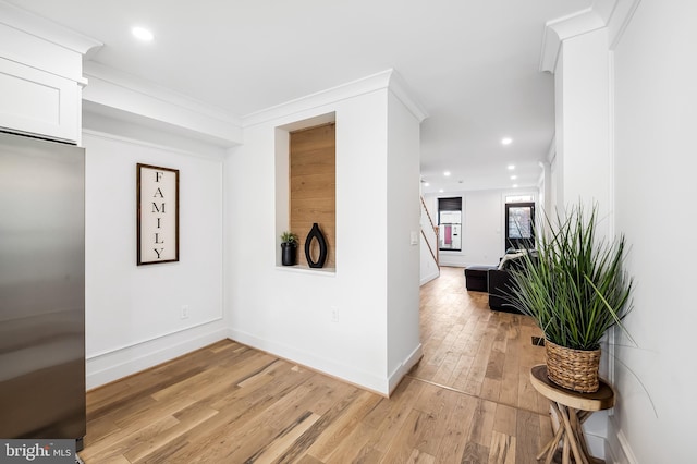 hall with ornamental molding and light hardwood / wood-style flooring