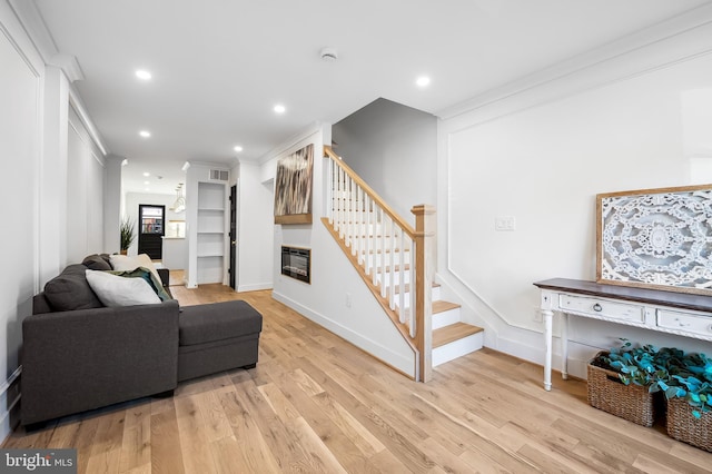 living room with light wood-type flooring and ornamental molding