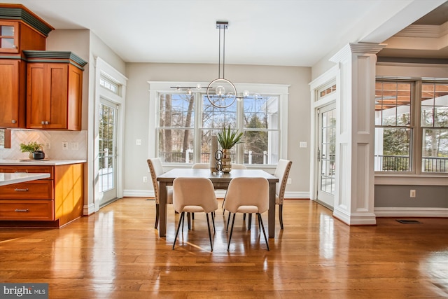 dining room featuring decorative columns, hardwood / wood-style flooring, and an inviting chandelier