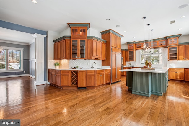 kitchen with a center island, decorative light fixtures, ornate columns, and light hardwood / wood-style floors