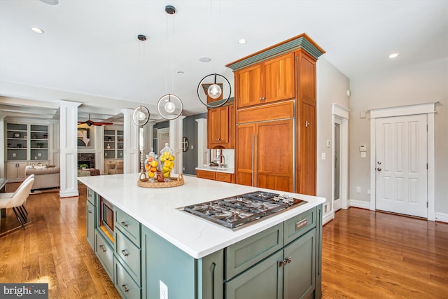 kitchen featuring pendant lighting, a center island, built in appliances, ceiling fan, and light wood-type flooring