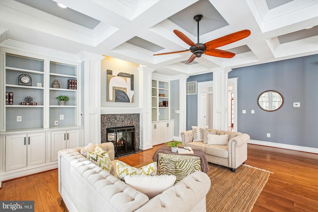 living room featuring ceiling fan, built in features, a premium fireplace, and coffered ceiling