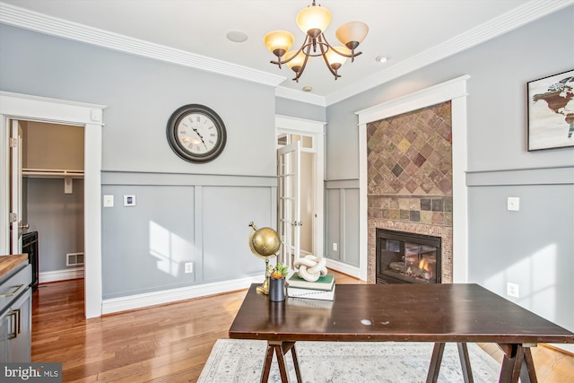 office featuring hardwood / wood-style flooring, ornamental molding, a tile fireplace, and a chandelier