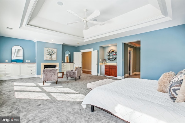 bedroom featuring a tray ceiling, ceiling fan, and light carpet