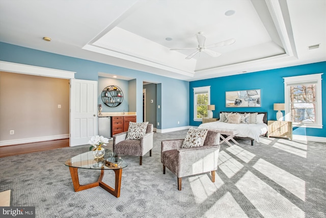 bedroom with ceiling fan, refrigerator, a raised ceiling, and carpet floors