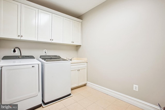 washroom featuring washing machine and dryer, sink, light tile patterned floors, and cabinets