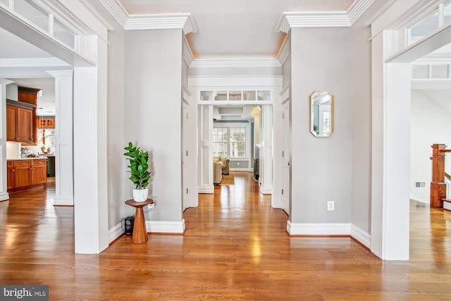 hallway featuring light wood-type flooring, crown molding, and sink