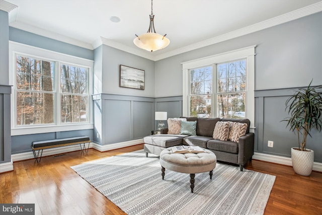 sitting room with a wealth of natural light, hardwood / wood-style floors, and ornamental molding