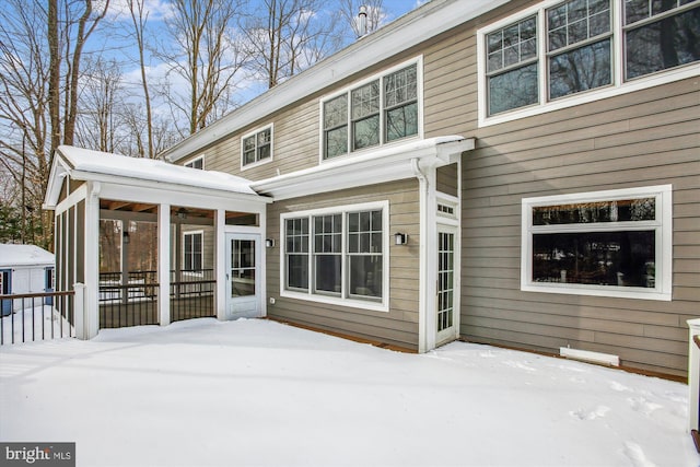 snow covered house featuring a sunroom