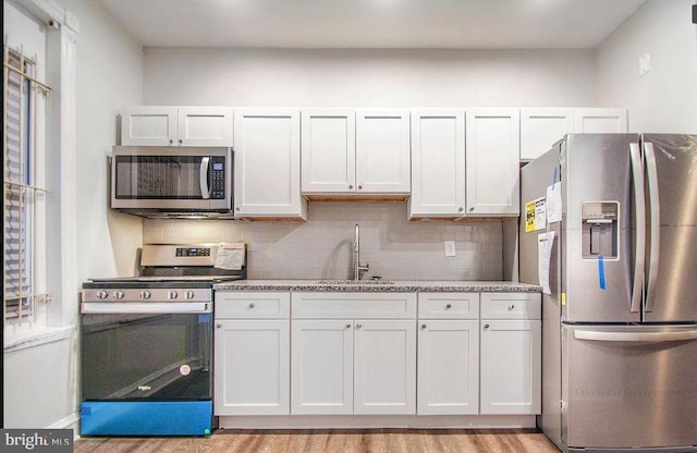 kitchen featuring sink, white cabinets, light wood-type flooring, and appliances with stainless steel finishes