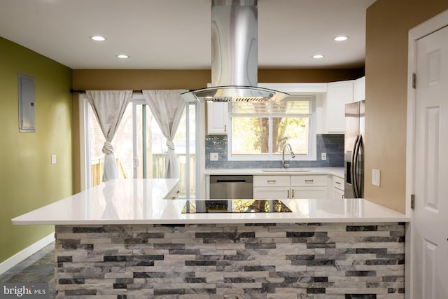 kitchen with island exhaust hood, appliances with stainless steel finishes, backsplash, sink, and white cabinets