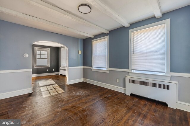 unfurnished room with dark wood-type flooring, beam ceiling, and radiator