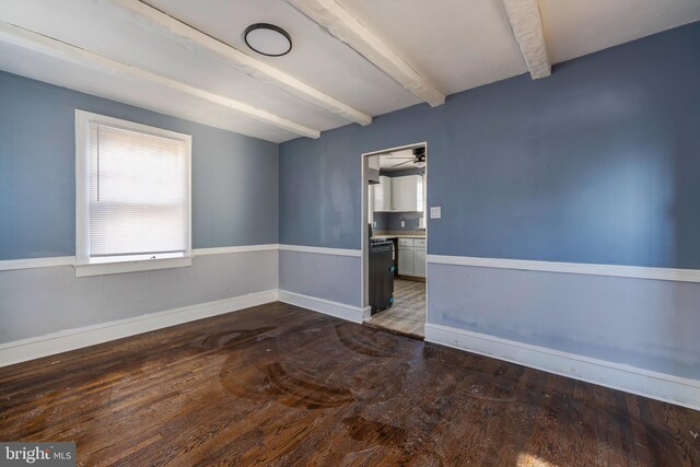 spare room featuring beam ceiling and dark hardwood / wood-style flooring