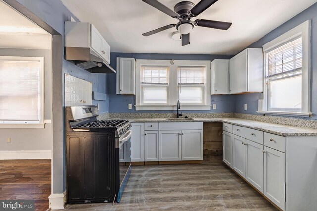 kitchen with dark hardwood / wood-style floors, white cabinetry, ceiling fan, stainless steel range with gas stovetop, and sink