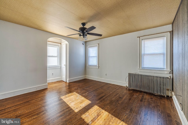 spare room featuring ceiling fan, radiator heating unit, and dark hardwood / wood-style floors