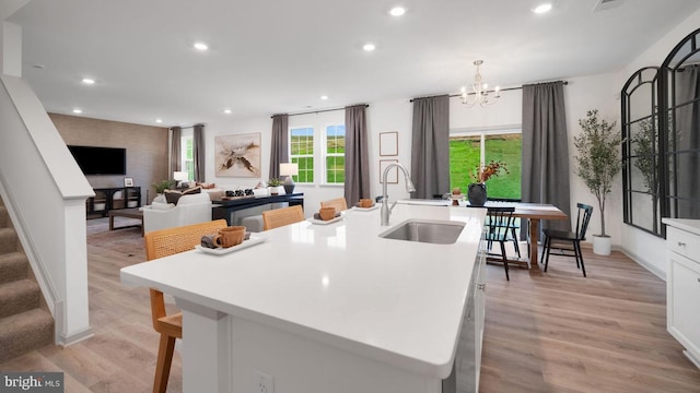 kitchen featuring white cabinets, sink, light hardwood / wood-style floors, and an island with sink