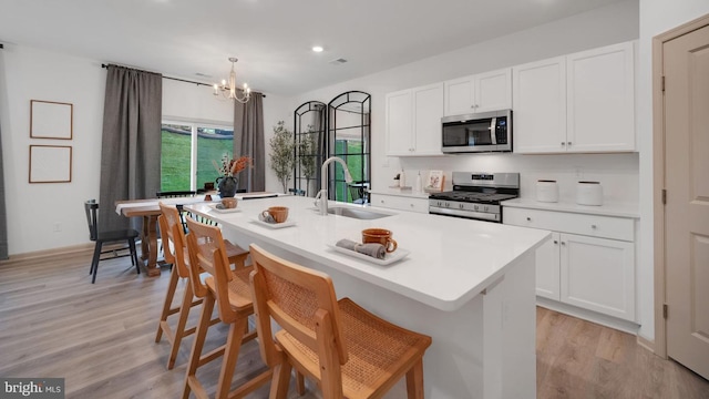 kitchen with stainless steel appliances, an inviting chandelier, a center island with sink, and sink