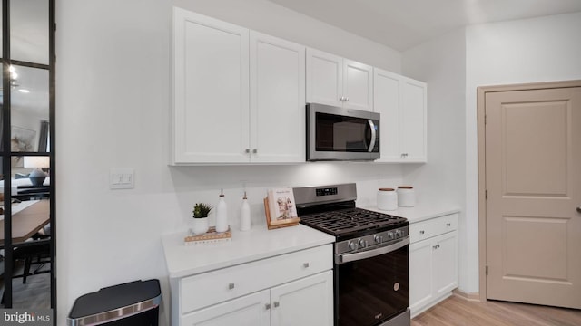 kitchen with white cabinets, stainless steel appliances, and light hardwood / wood-style floors