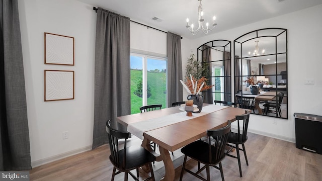 dining space with light hardwood / wood-style floors and a chandelier