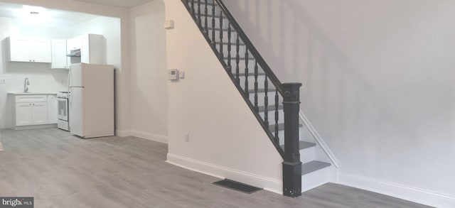 stairs featuring hardwood / wood-style flooring and sink