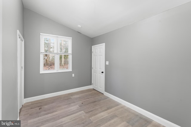 unfurnished room featuring light hardwood / wood-style floors and lofted ceiling