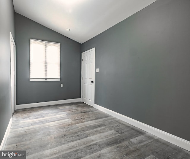 spare room featuring lofted ceiling and hardwood / wood-style flooring