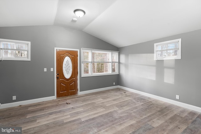 foyer entrance featuring light hardwood / wood-style floors, a wealth of natural light, and vaulted ceiling