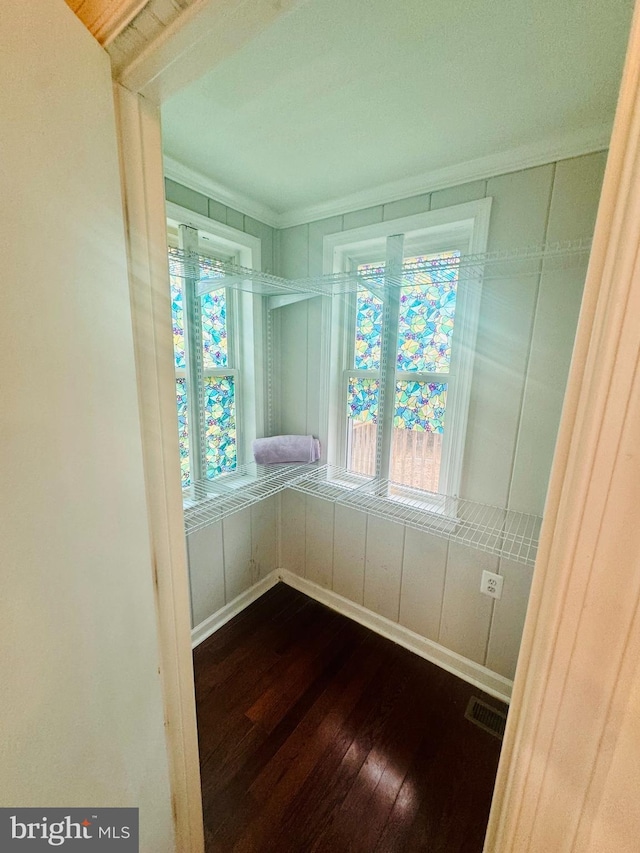 empty room with ornamental molding, a healthy amount of sunlight, and dark hardwood / wood-style flooring