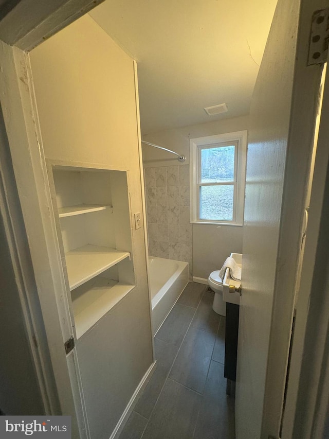 bathroom with tiled shower / bath combo and toilet