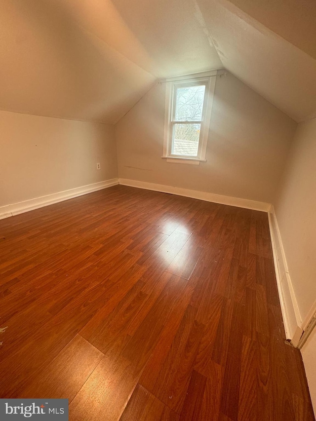 additional living space with hardwood / wood-style floors and vaulted ceiling