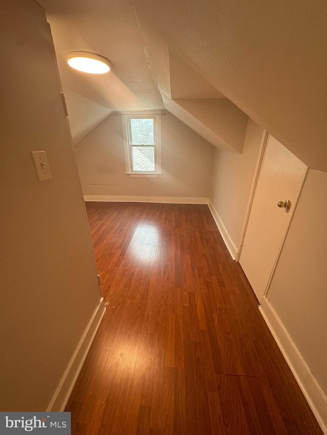 additional living space featuring vaulted ceiling and dark hardwood / wood-style floors