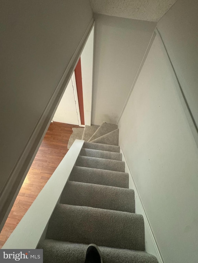 stairway featuring hardwood / wood-style flooring and a textured ceiling