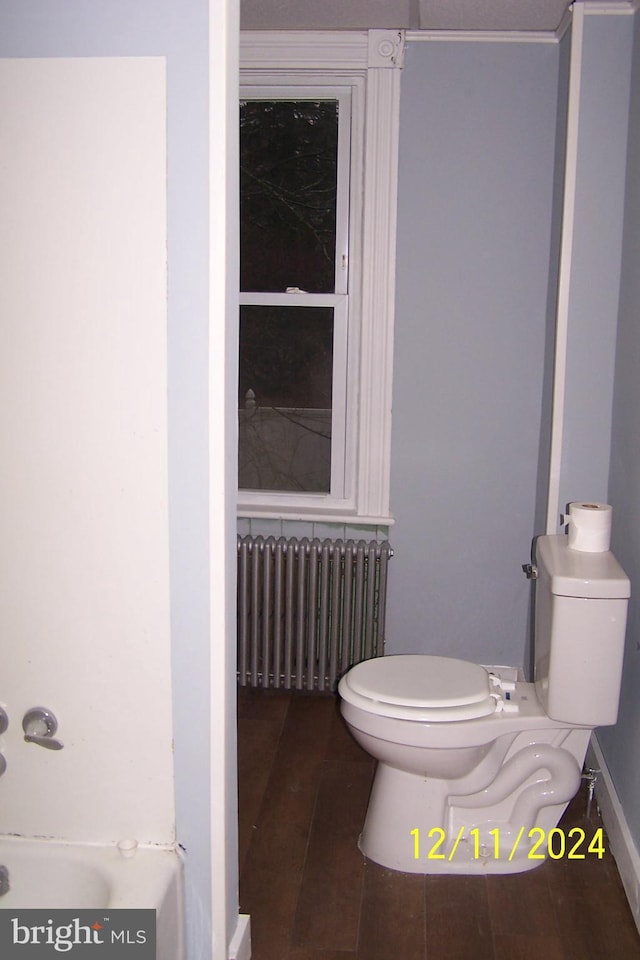 bathroom featuring hardwood / wood-style flooring, radiator heating unit, and toilet