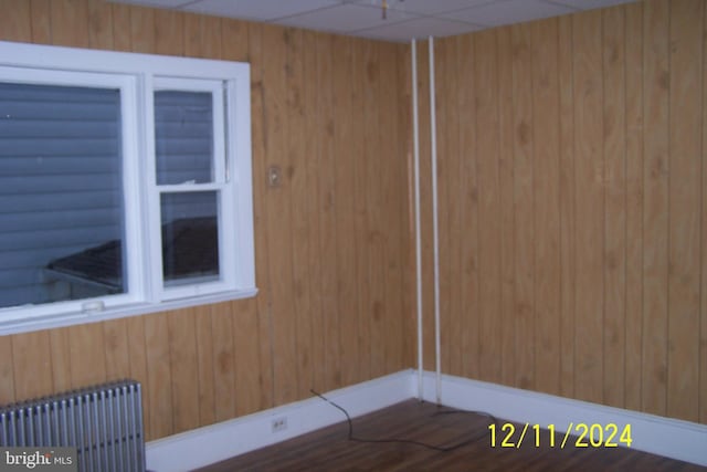 spare room featuring a paneled ceiling, wood walls, and radiator