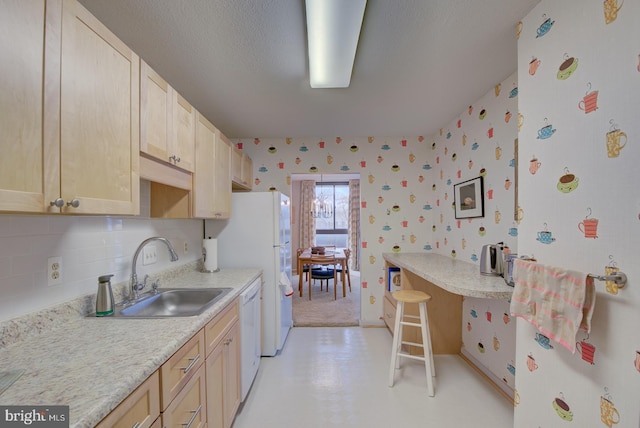 kitchen with dishwasher, light brown cabinetry, decorative backsplash, and sink