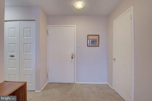 hall featuring a textured ceiling and light carpet