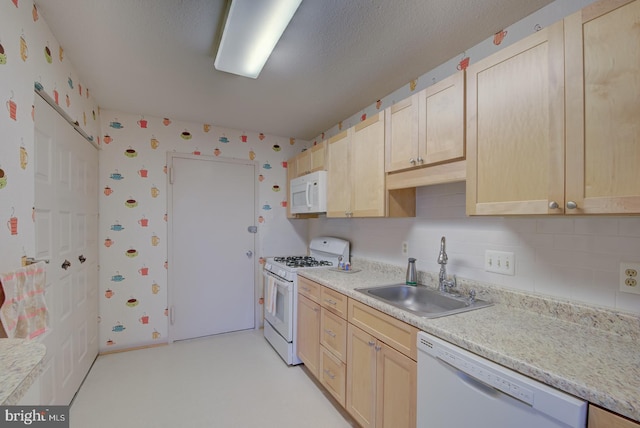 kitchen featuring white appliances, sink, and light brown cabinetry