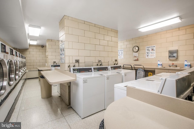 laundry area with washing machine and dryer, sink, and tile walls