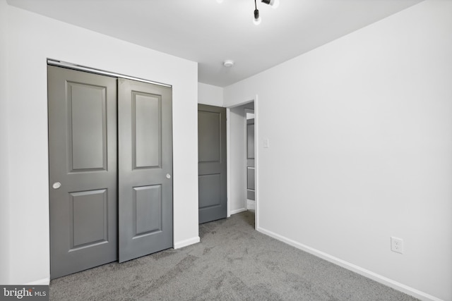 unfurnished bedroom featuring a closet and light colored carpet