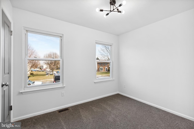 empty room featuring a chandelier and carpet