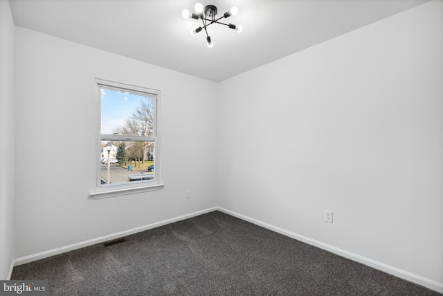 carpeted spare room with a notable chandelier