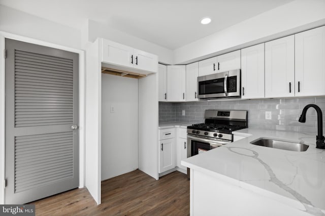 kitchen with white cabinets, sink, light stone countertops, and stainless steel appliances