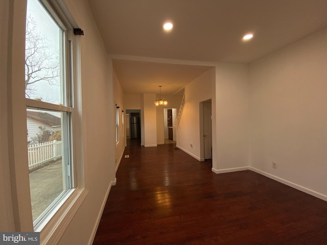 corridor featuring a chandelier and dark wood-type flooring