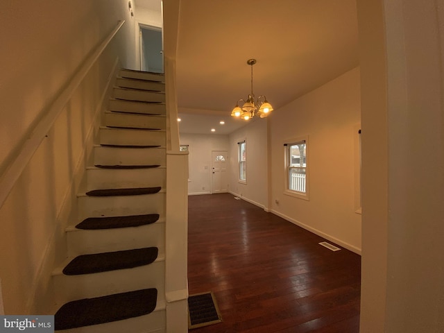 stairs featuring hardwood / wood-style floors and an inviting chandelier