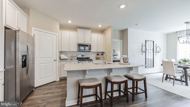 kitchen with a center island with sink, sink, dark hardwood / wood-style floors, white cabinetry, and stainless steel appliances