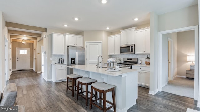 kitchen featuring white cabinetry, stainless steel appliances, and an island with sink